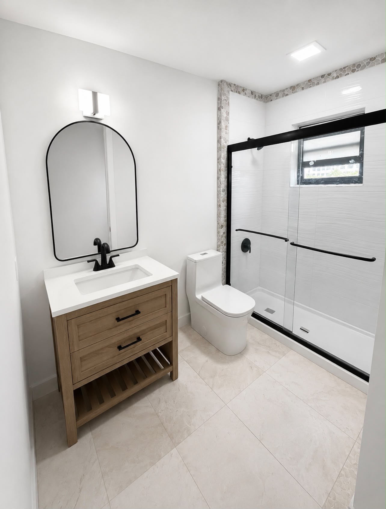 Completed bathroom remodel with new vanity, arched mirror and glass-door shower