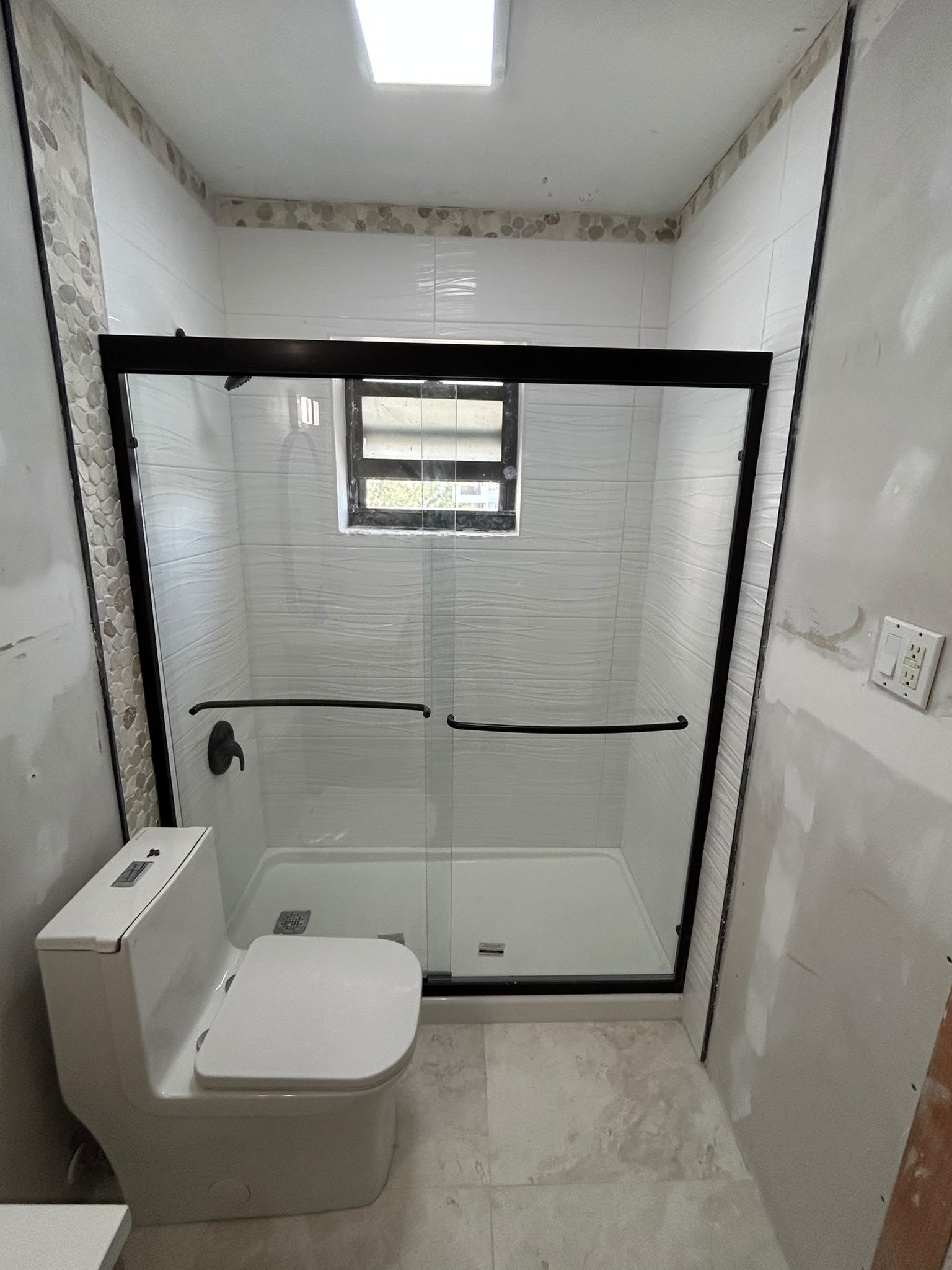 Finished shower with sliding glass doors and matte black fixtures