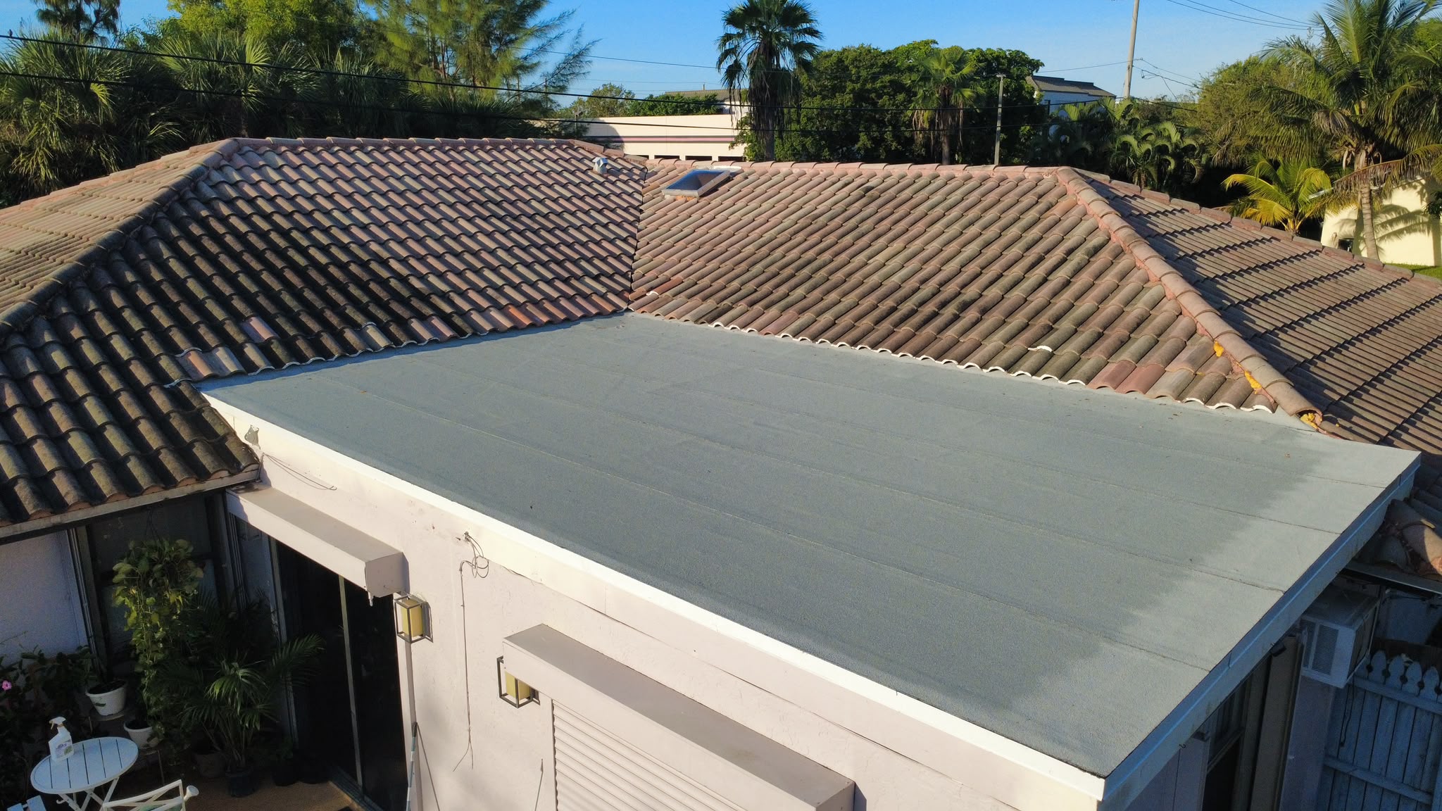 Low aerial view of finished flat roof section beside tile roof
