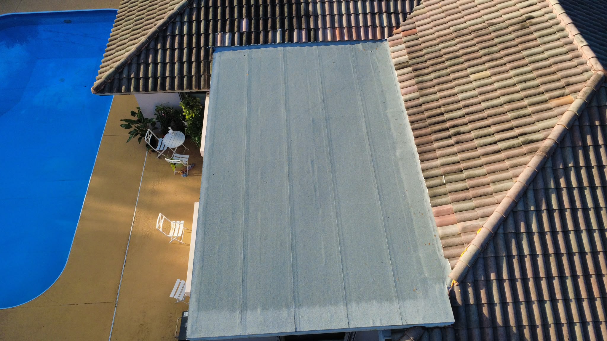 Top-down aerial view of flat roof section next to pool deck