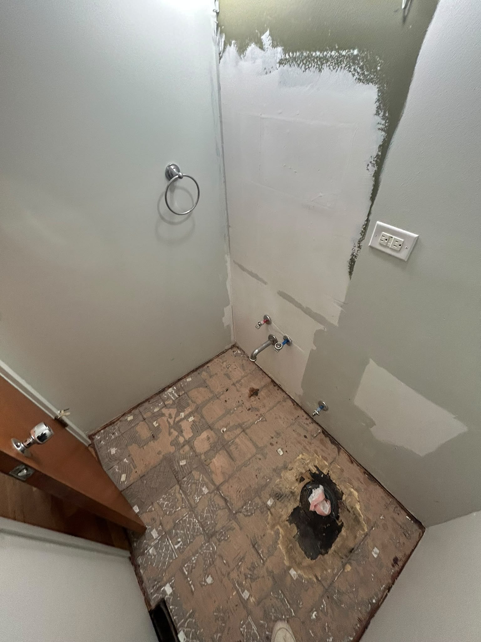 Powder room after demolition with fixtures removed and subfloor exposed
