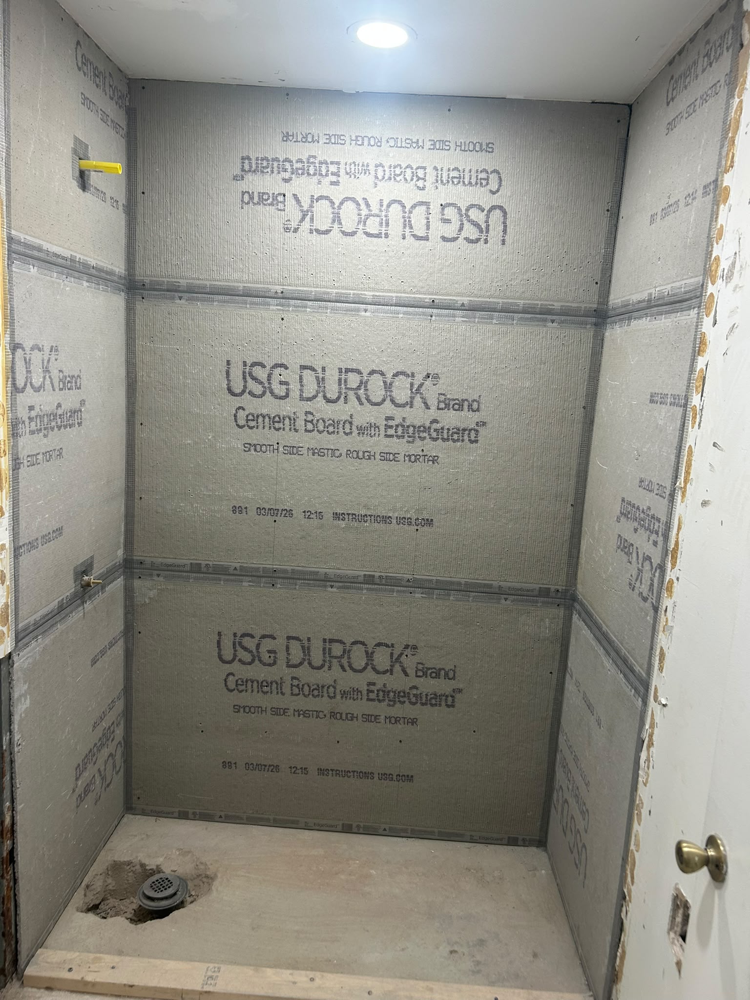 Shower walls lined with cement board and drain rough-in