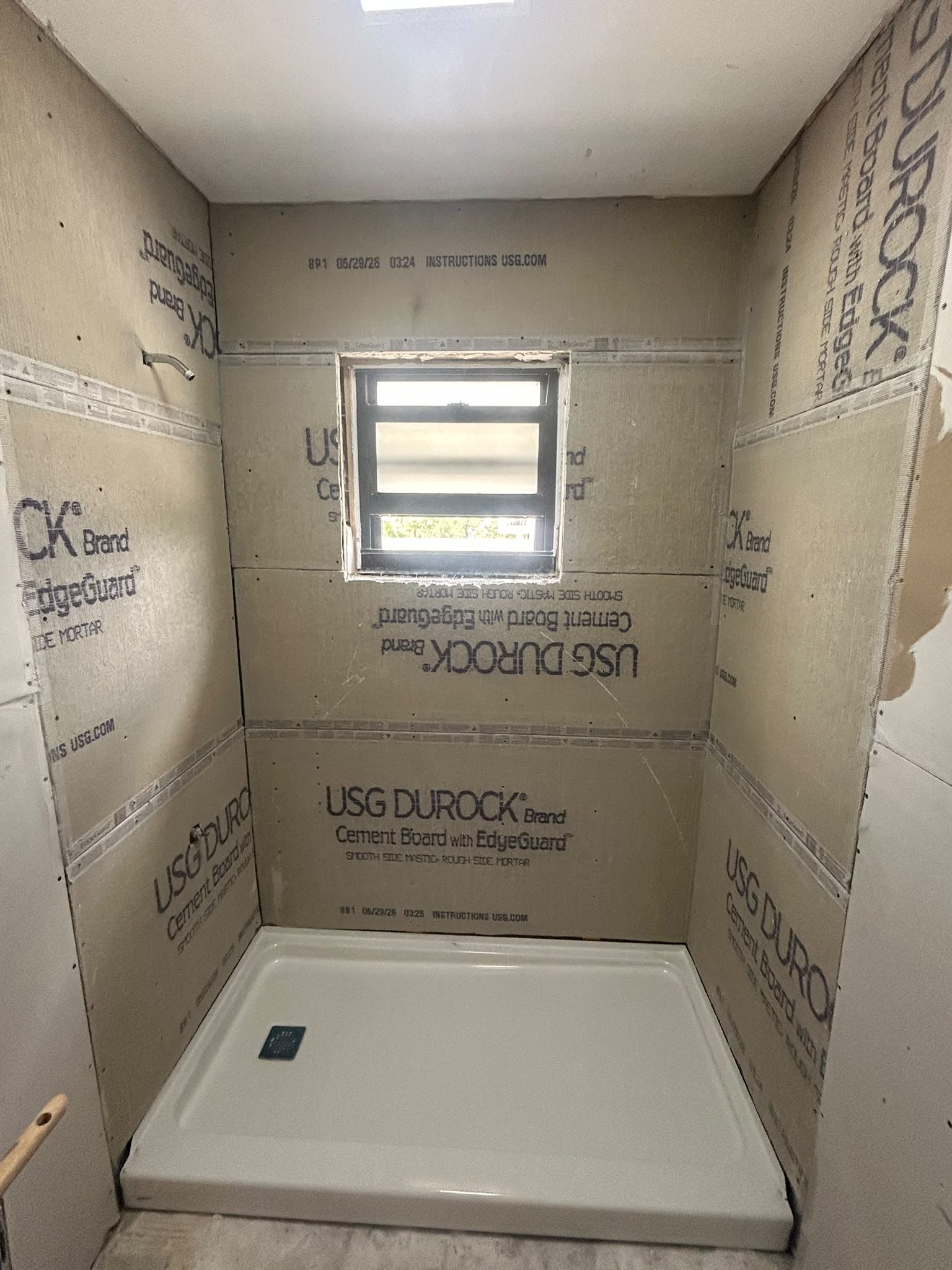 New shower pan set against cement board walls