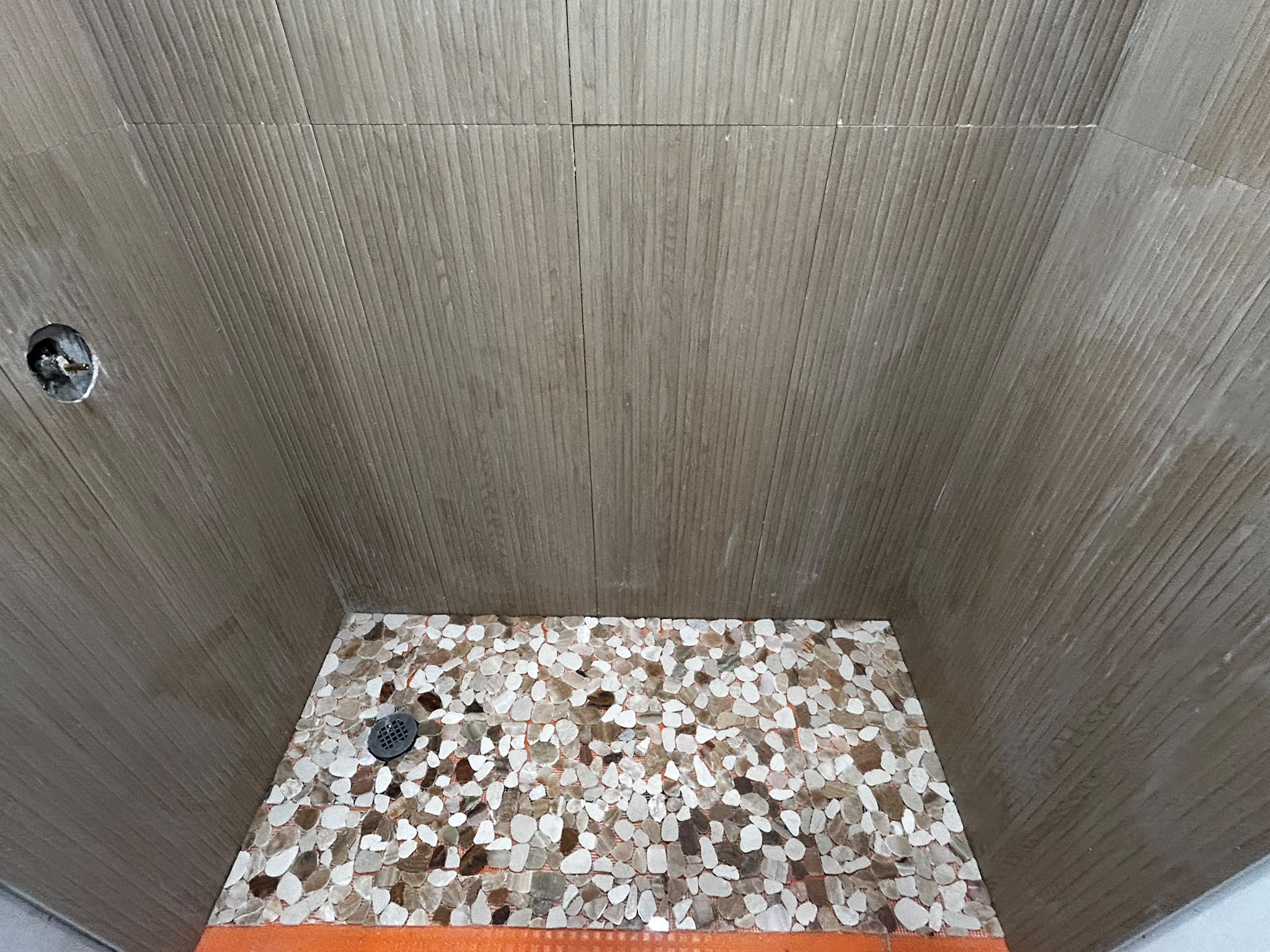 Pebble mosaic shower floor with ribbed wall tile